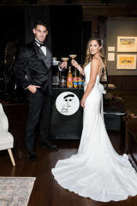 Newly married couple standing in front of a coffee cart indoors toasting with espresso martinis. Photo: Christian Napolitano